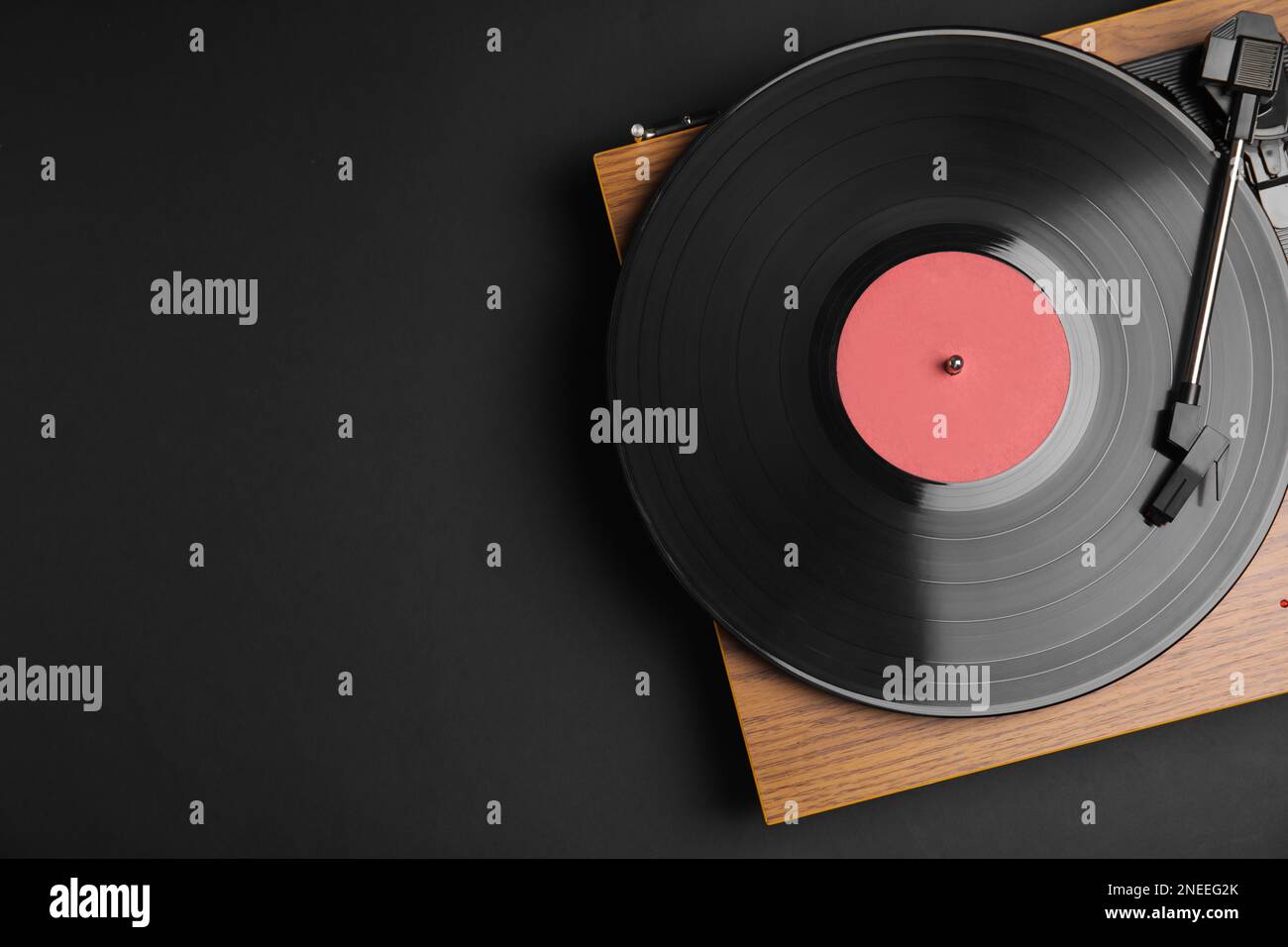 Modern vinyl record player with disc on black background, top view
