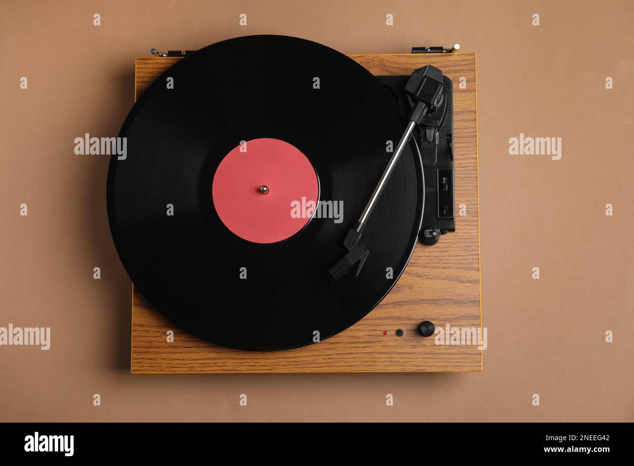 Modern vinyl record player with disc on brown background, top view