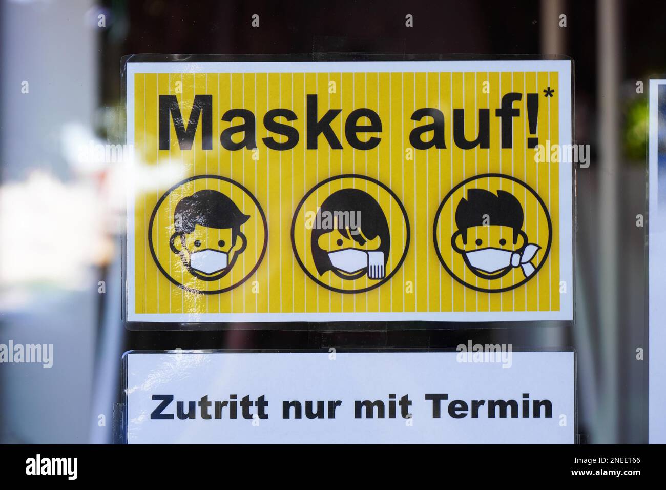 Hannover, Germany - June 1, 2020: German language sign on entrance door to tattoo parlor advises that face mask is mandatory and entry by appointment Stock Photo