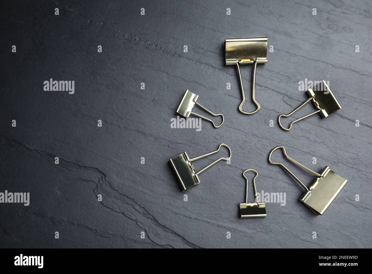 Binder clips on black background, flat lay. Space for text Stock Photo