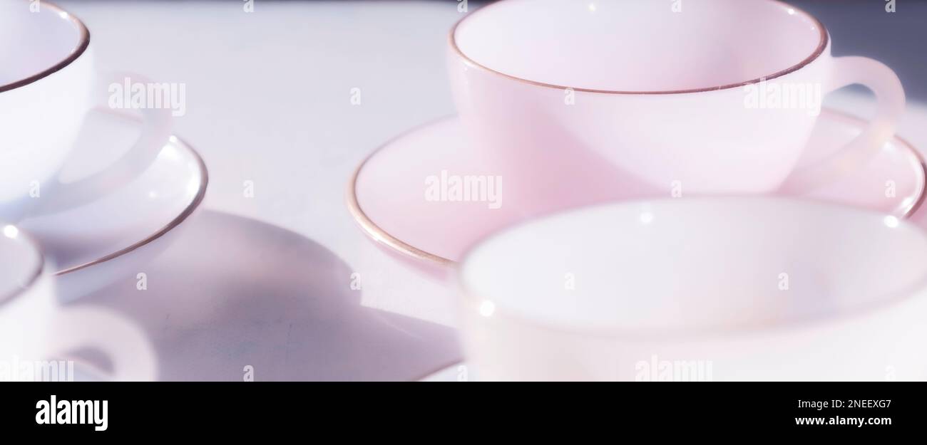 Minimalist delicate light bright abstract dreamy soft background of glass teacups and saucers in milky pastel colours, British afternoon tea concept Stock Photo