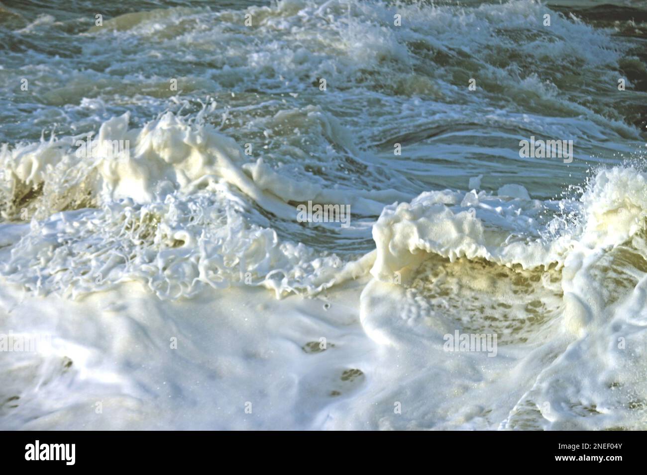 The mist of the waves when they reach the sand on the beach. The foam that paints abstract and beautiful images. It's nature in all its forms. Stock Photo