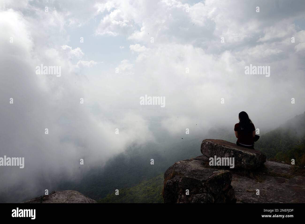 A girl looks out over the clouds at Bokor Mountain in Cambodia. Stock Photo