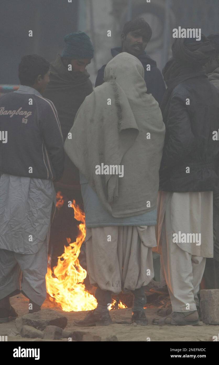People stand near a fire as fog envelopes Lahore, Pakistan, on Monday