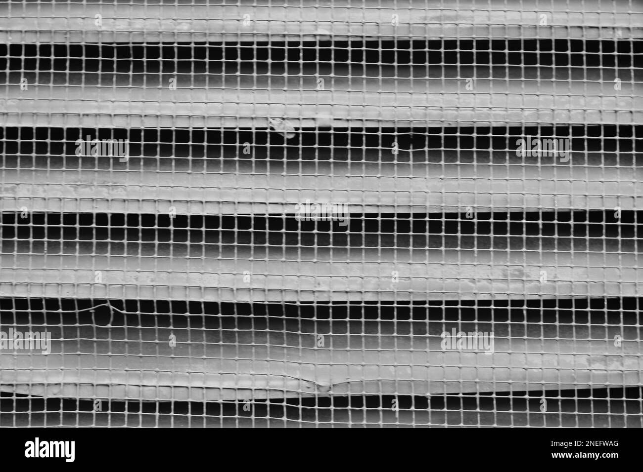 Typical common chicken wire spread across wooden supports in a black