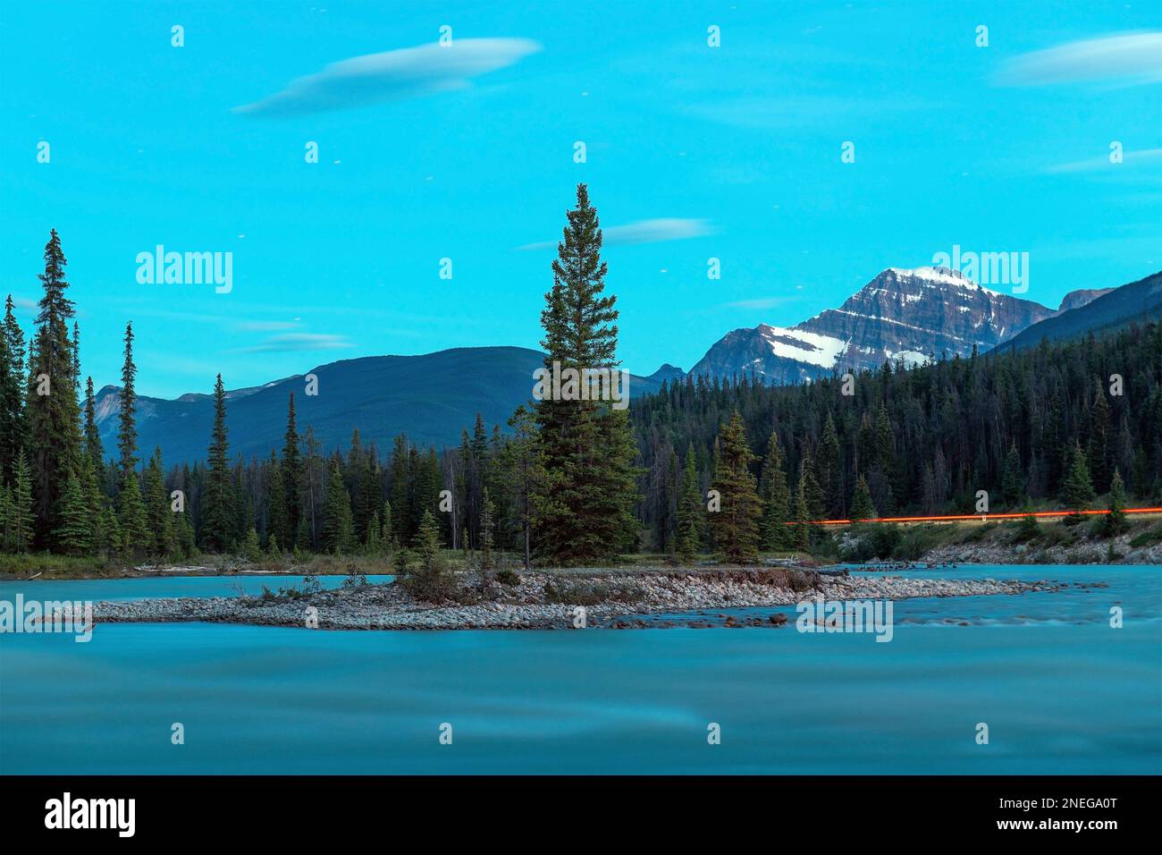 Athabasca river at night with star trails and red car light along highway with Mount Edith Cavell in background, Jasper national park, Canada. Stock Photo