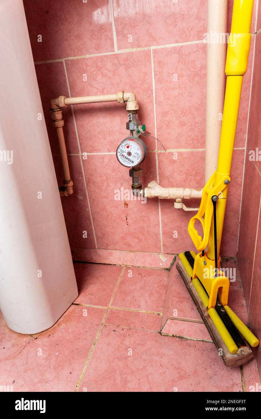 old water pipes with a utility water meter. an old dirty bathroom Stock