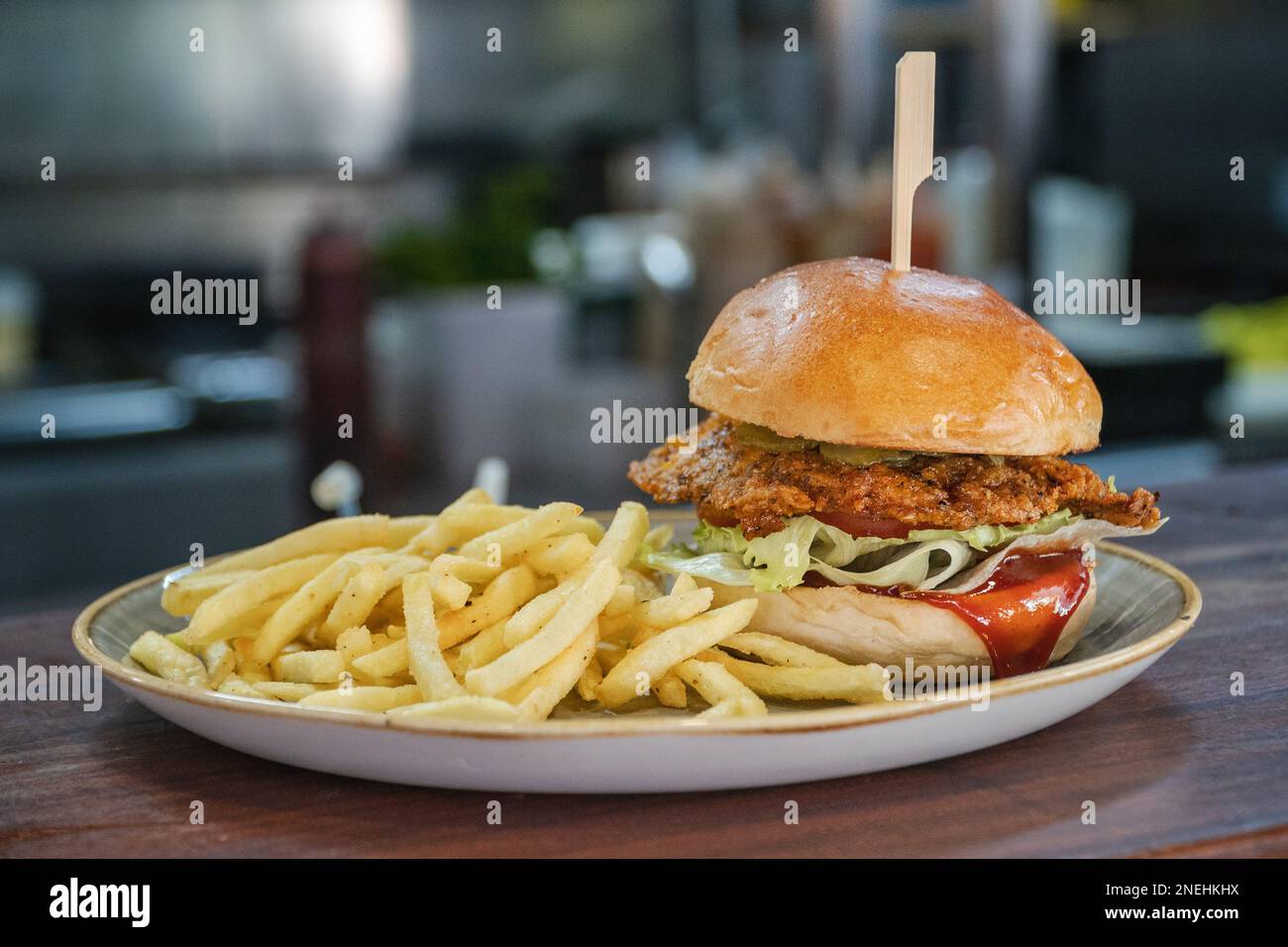 A tasty looking KFC style breaded chicken burger served alongside French Fries Stock Photo
