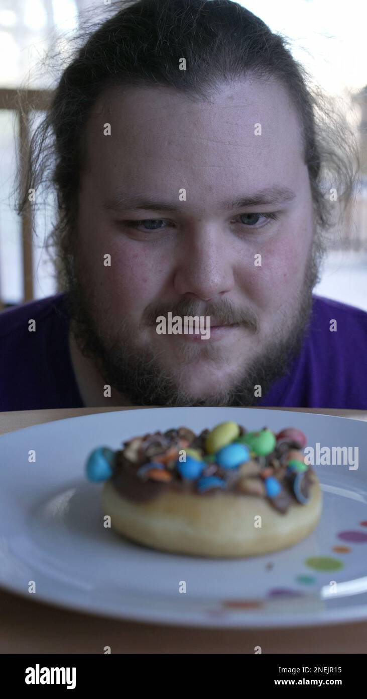 Overweight Person wanting to eat sugar food on plate. One Young fat man