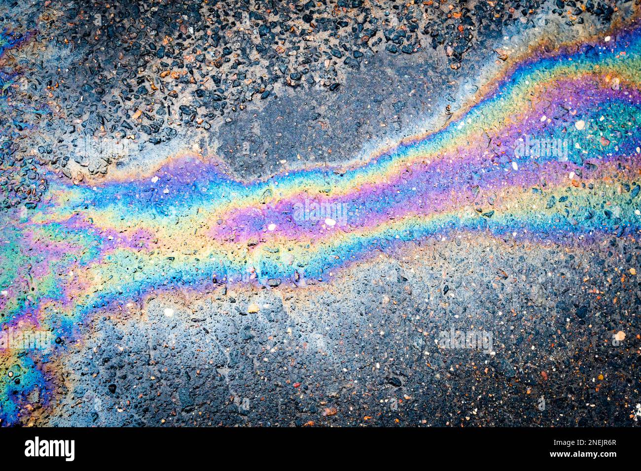 Iridescent oil or gasoline spill on a wet asphalt, viewed from above