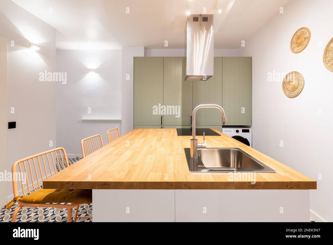 Designer kitchen with bright lighting from wall lamps. Table with sink and faucet in chromed