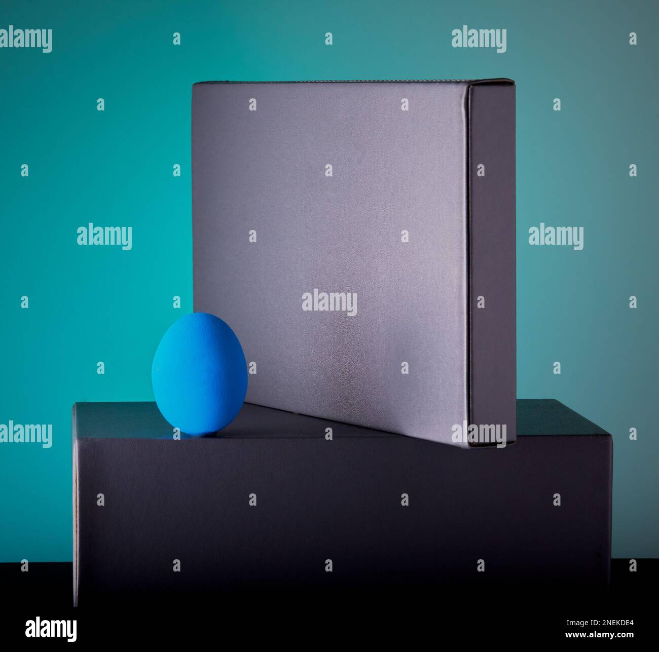 New beginnings concept with a blue egg on some studio blocks with a blue gradient background. Stock Photo