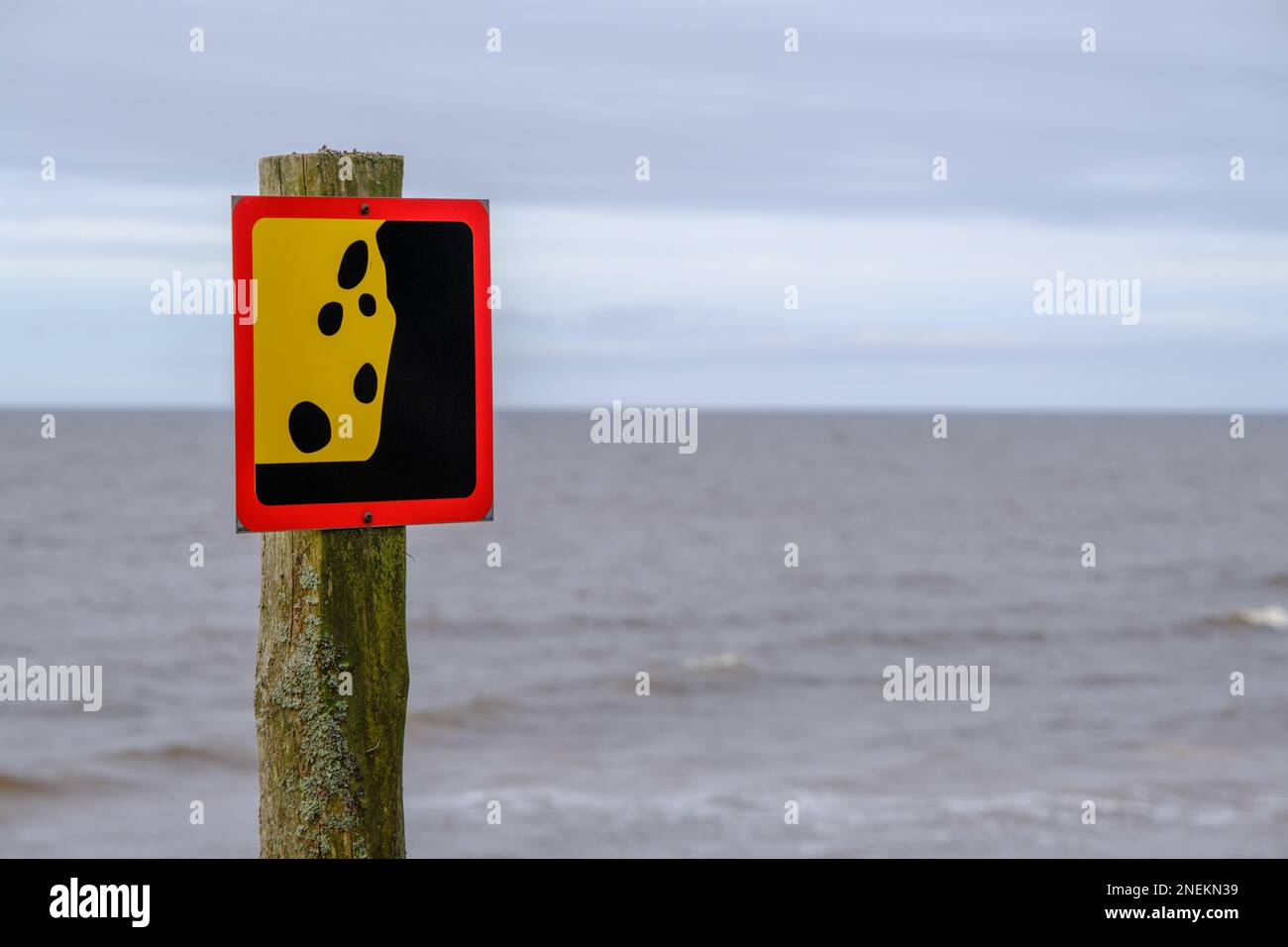 A warning sign about a possible landslide near the seashore. Reflects ...