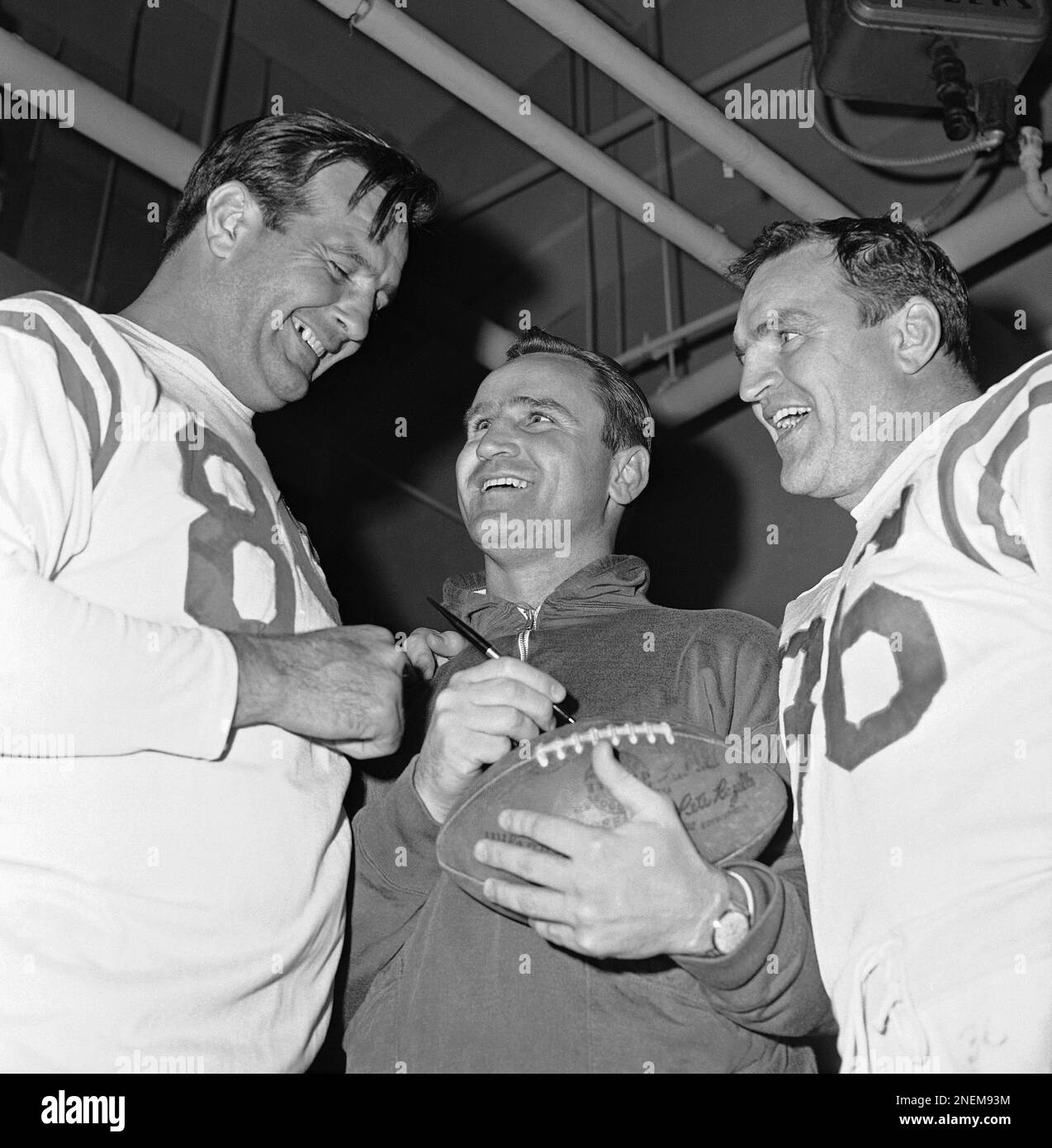 Don Shula, center, coach of the Baltimore Colts, Western Conference champs  in the National Football League, signs a football for two of his standout  defensive players after he was named NFL Coach