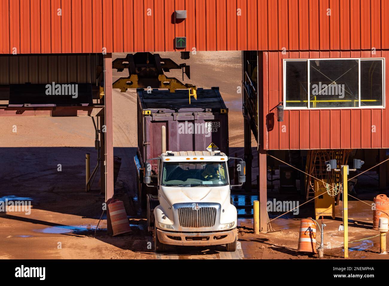 An empty container truck having its container cap removed at the UMTRA tailings project in Moab, Utah.  The hoist is sliding over the container to rem Stock Photo