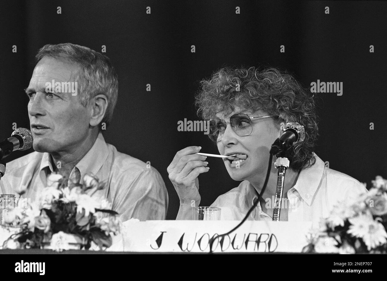 US actress Joanne Woodward eats a snack while husband Paul Newman answers newsmen about his film