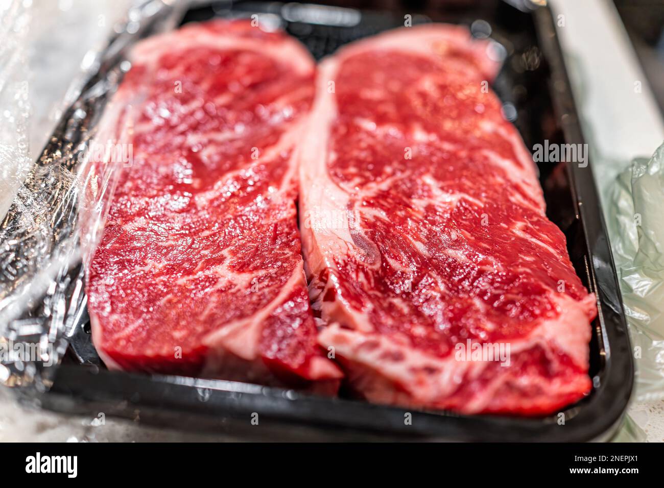 Two raw red strip steaks cuts of meat closeup macro of texture butcher