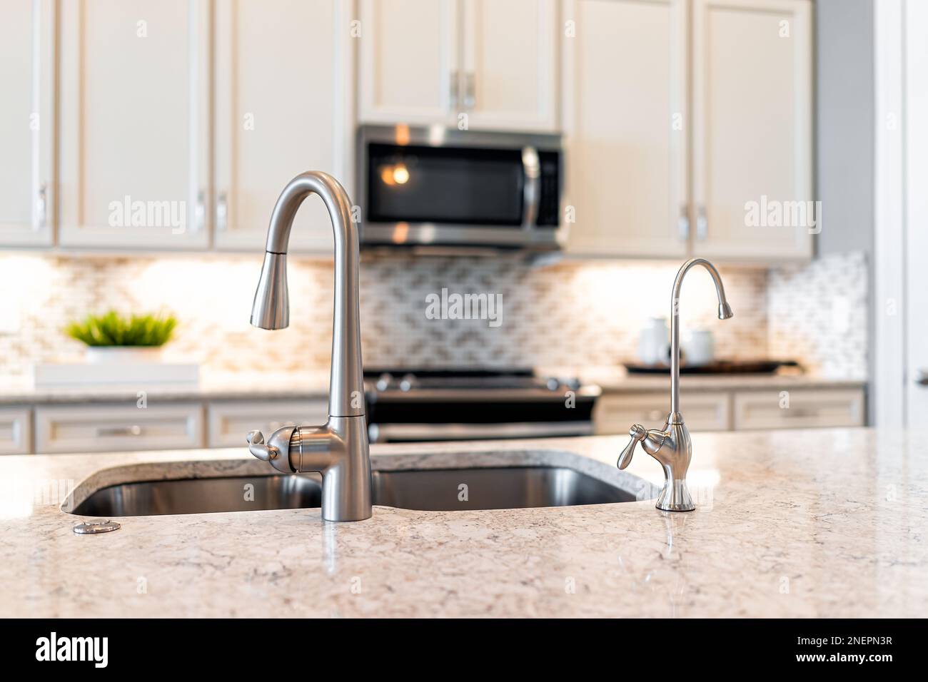 New modern faucet and kitchen sink closeup with island and granite
