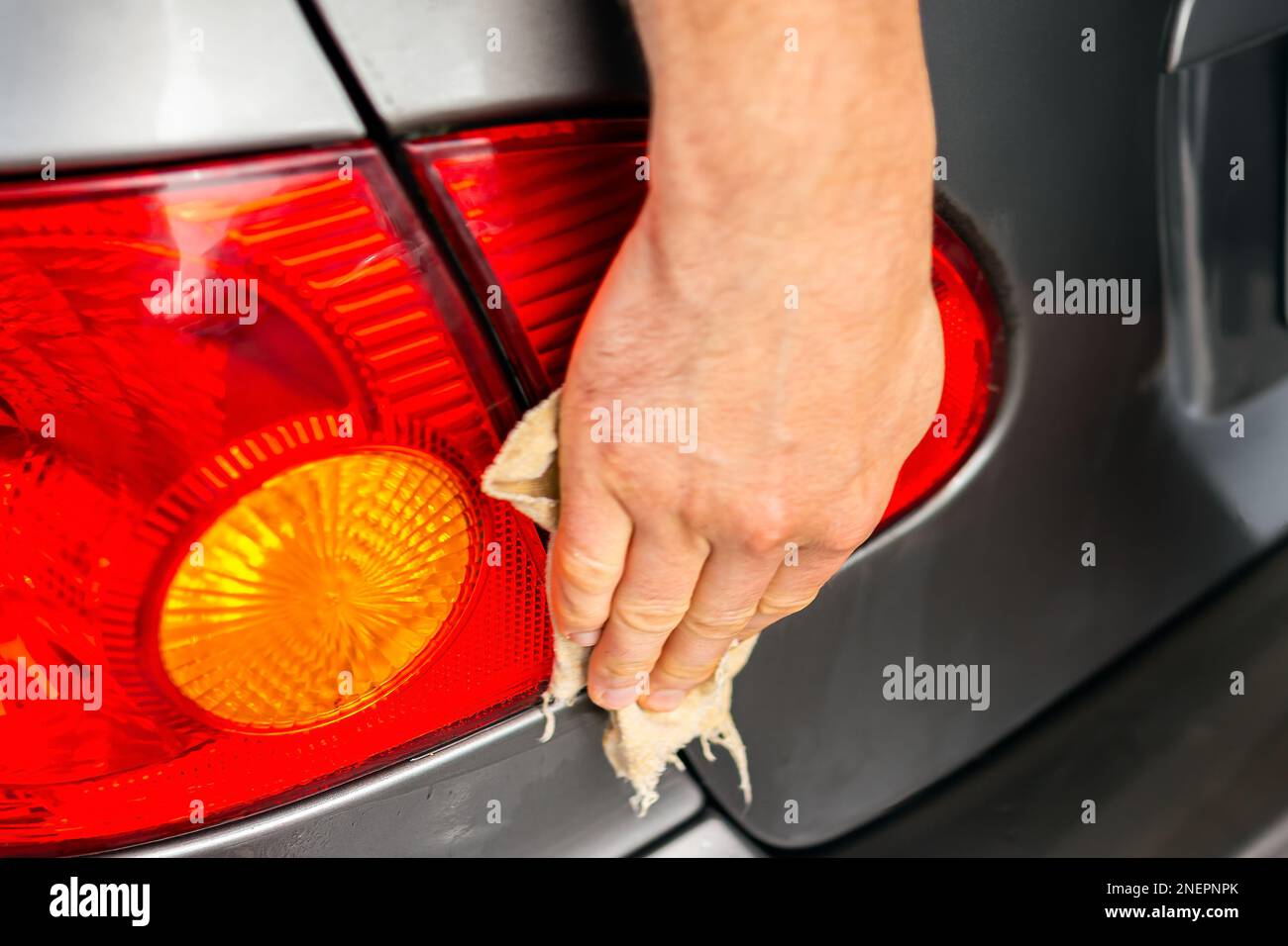 Car wash station, man washing wiping vehicle rear trunk lights closeup