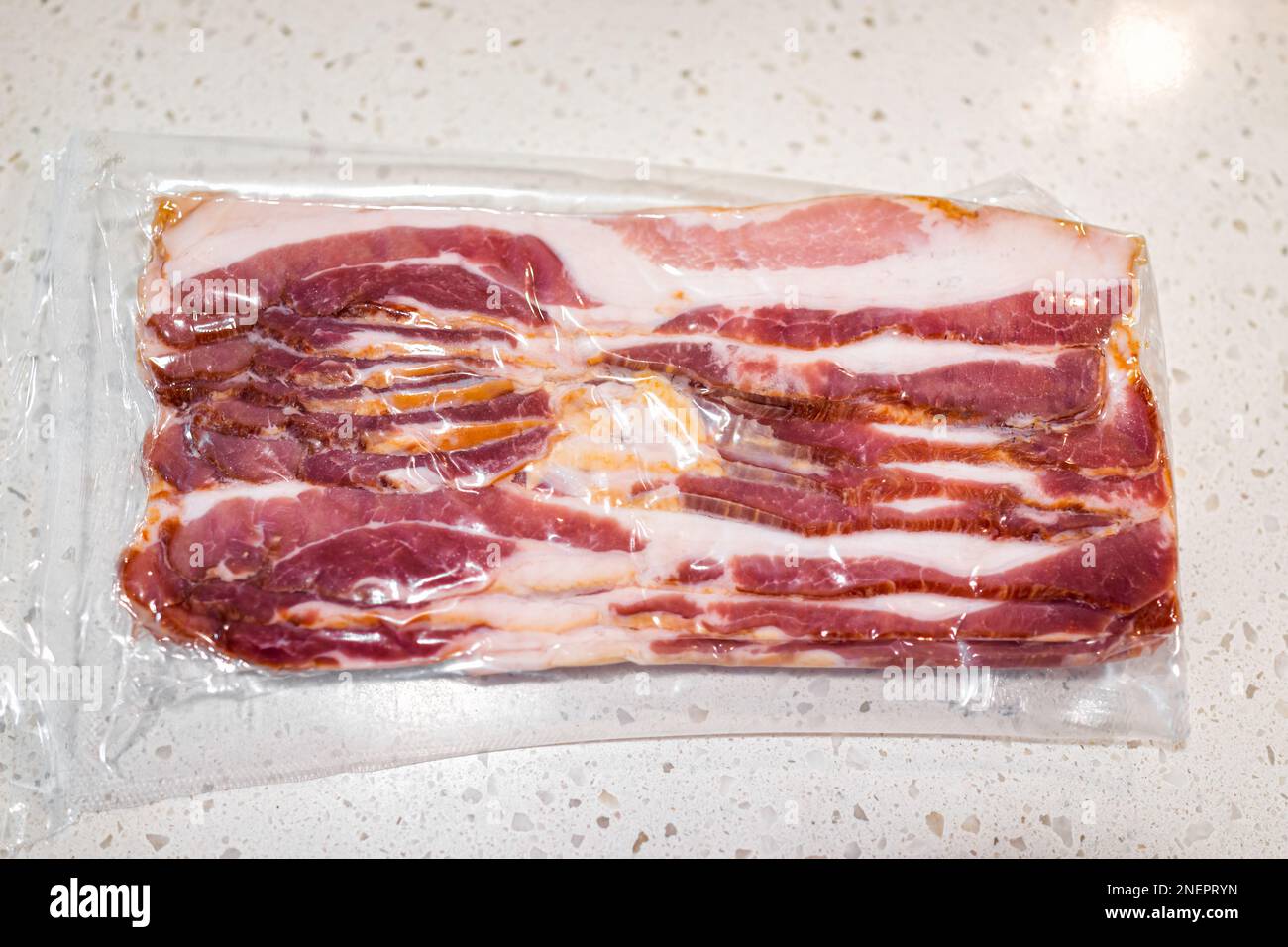 Raw uncured bacon meat vacuum sealed packaged in plastic closeup with fat and meat from above view Stock Photo