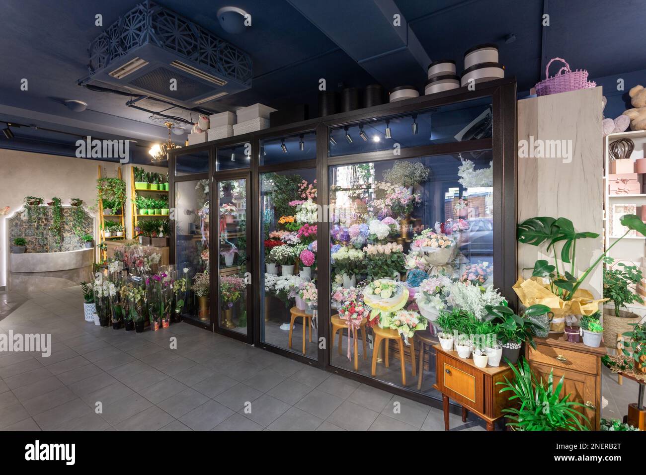 Flowers shop interior with cold storage for flowers demonstrating and saving. Shelves with decorative indoor plants, vases, pots, boxes, decorations a Stock Photo