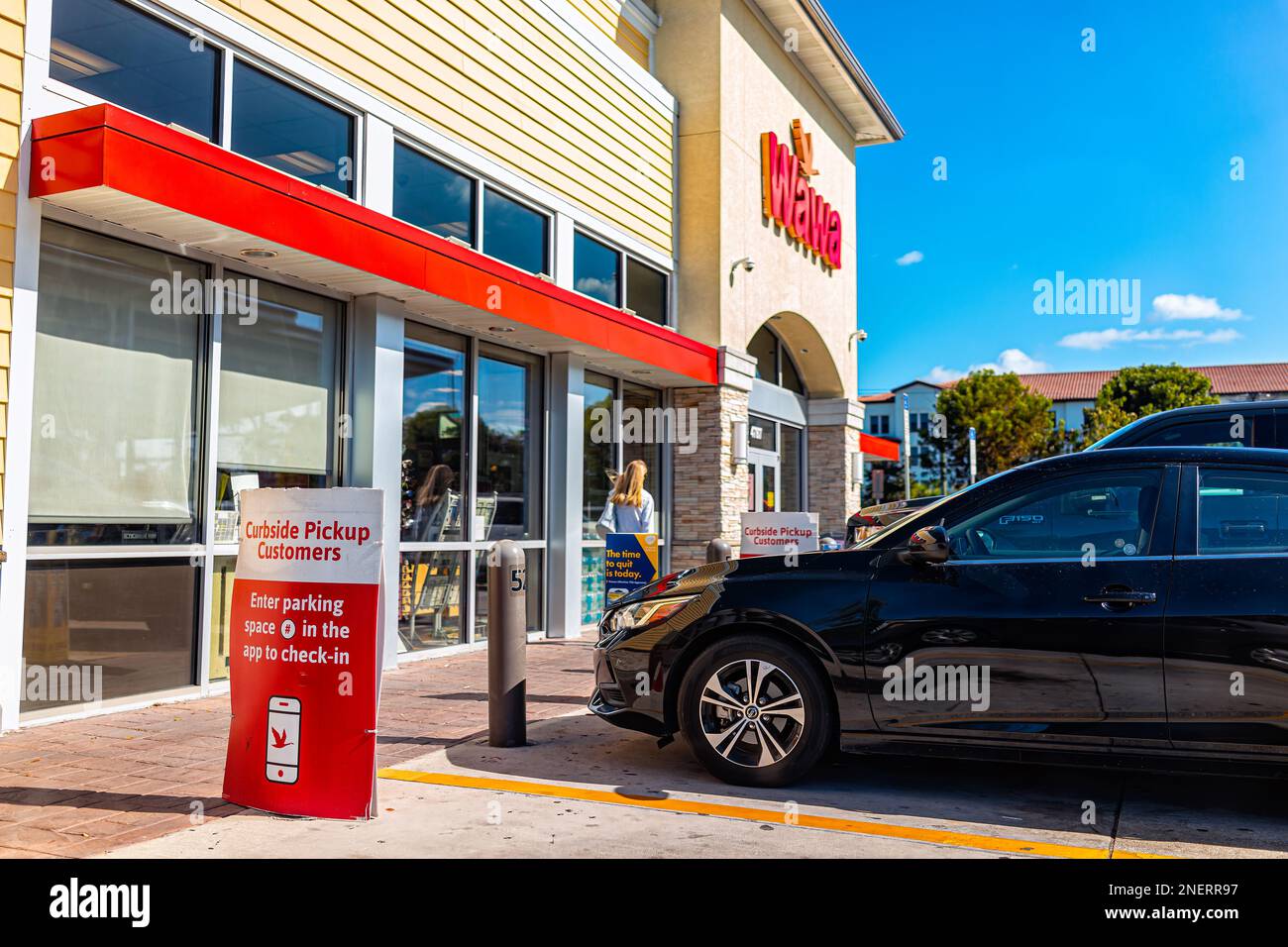 Naples, USA - January 12, 2022: Wawa gas station store exterior with sign for curbside pickup in Naples, Florida on Livingston road with cars in parki Stock Photo