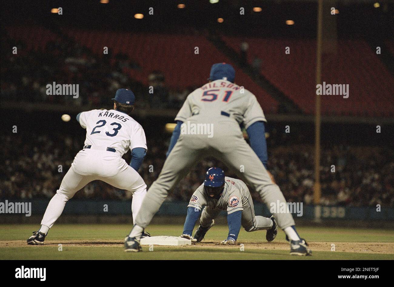 Carl Everett of the New York Mets, center, dives back to first base while Eric  Karros of the Los Angeles Dodgers, left, takes the throw from the pitcher  as Mets first base