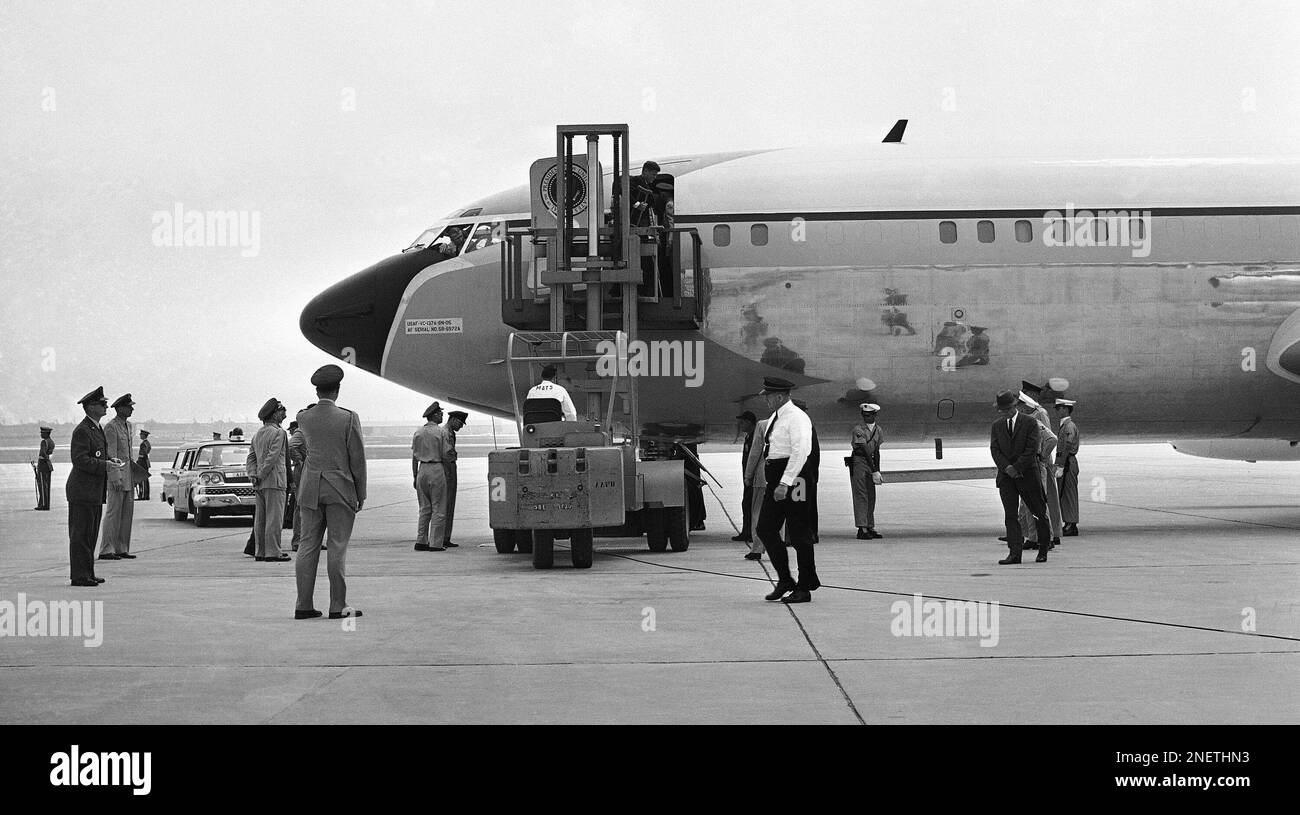 President John Kennedy, leaning on his left crutch and holding the other, comes out the door of