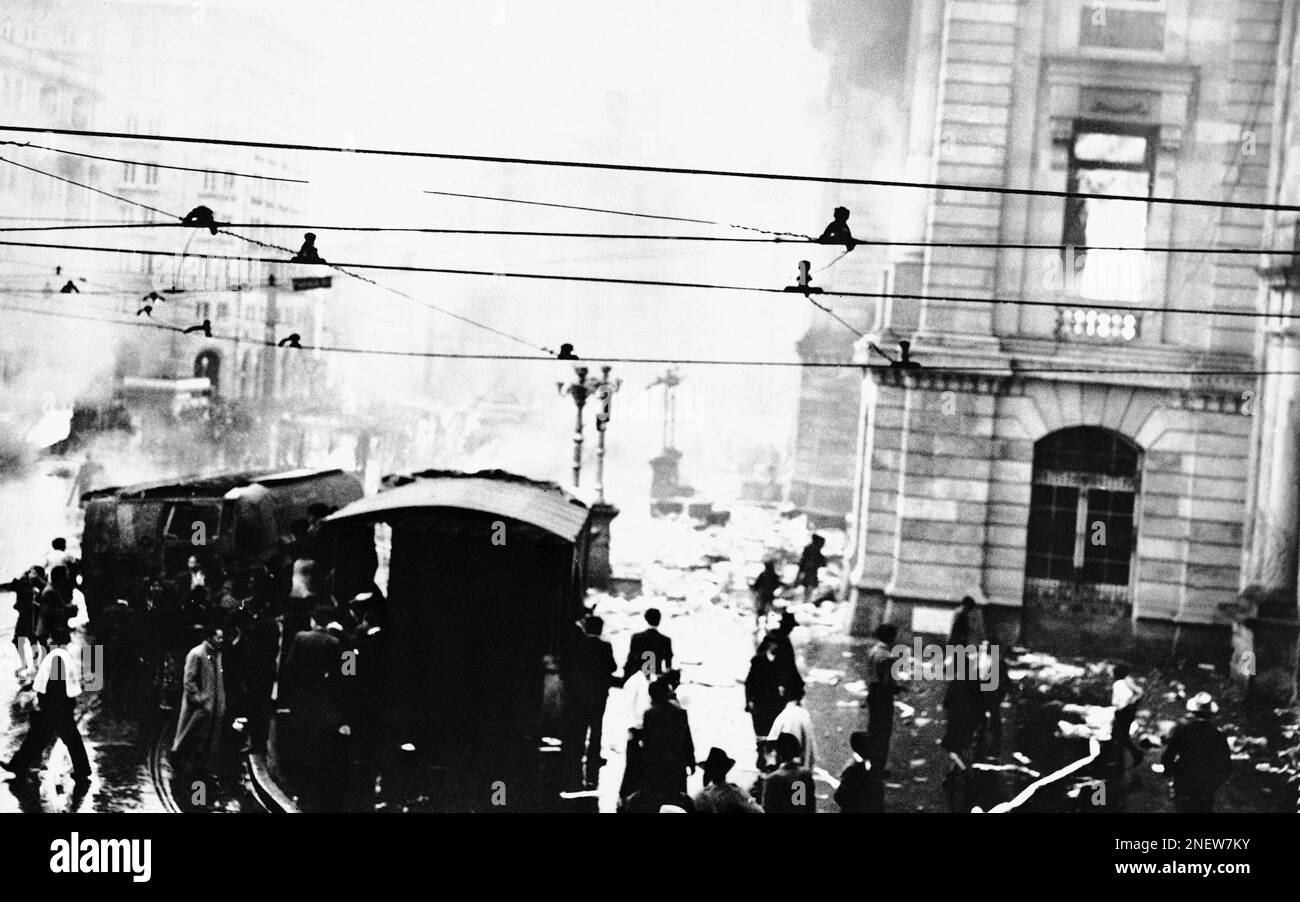 Crowds gather around smoking and burning streetcars which were ...