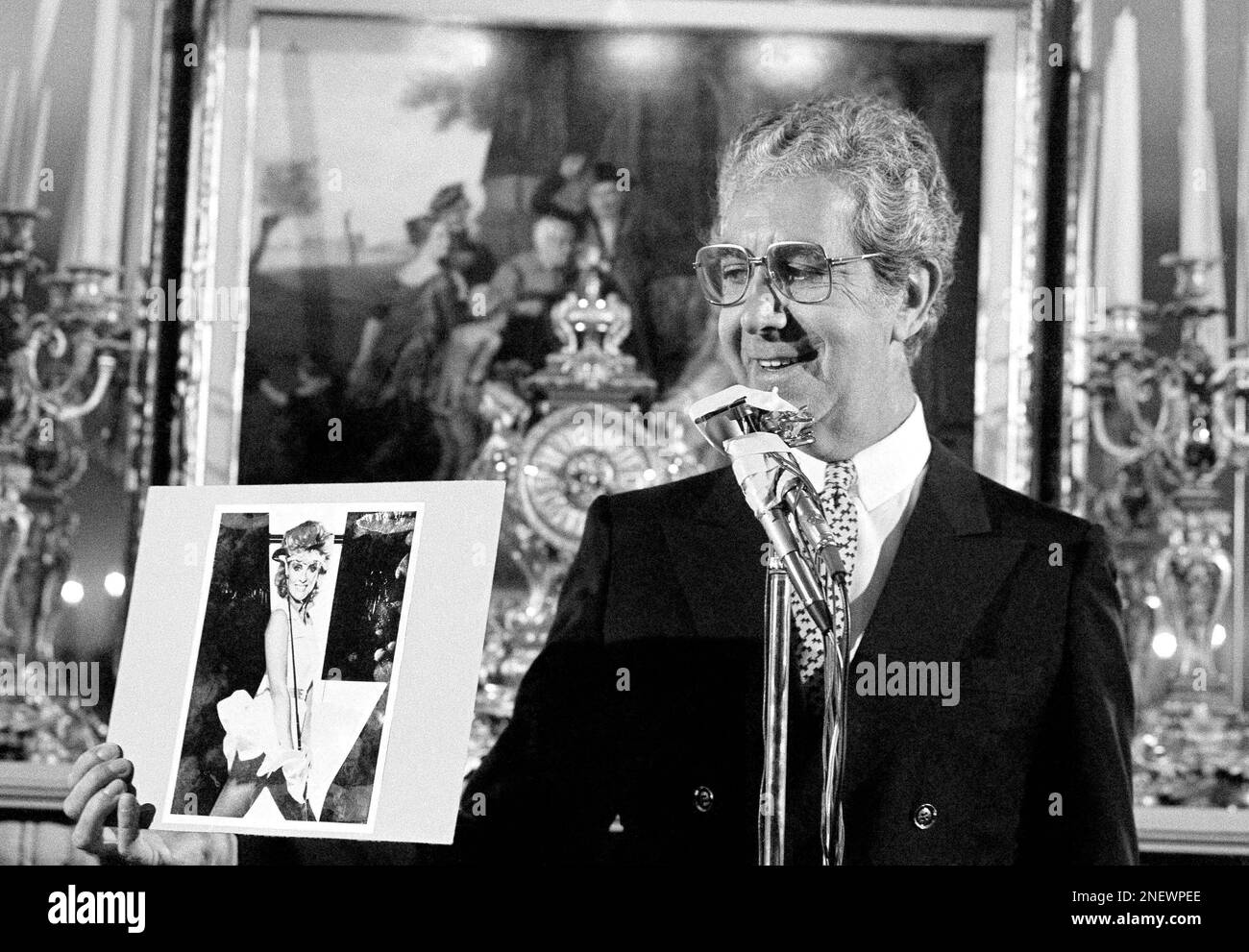 Fashion designer Mr. Blackwell holds photos of those included on his