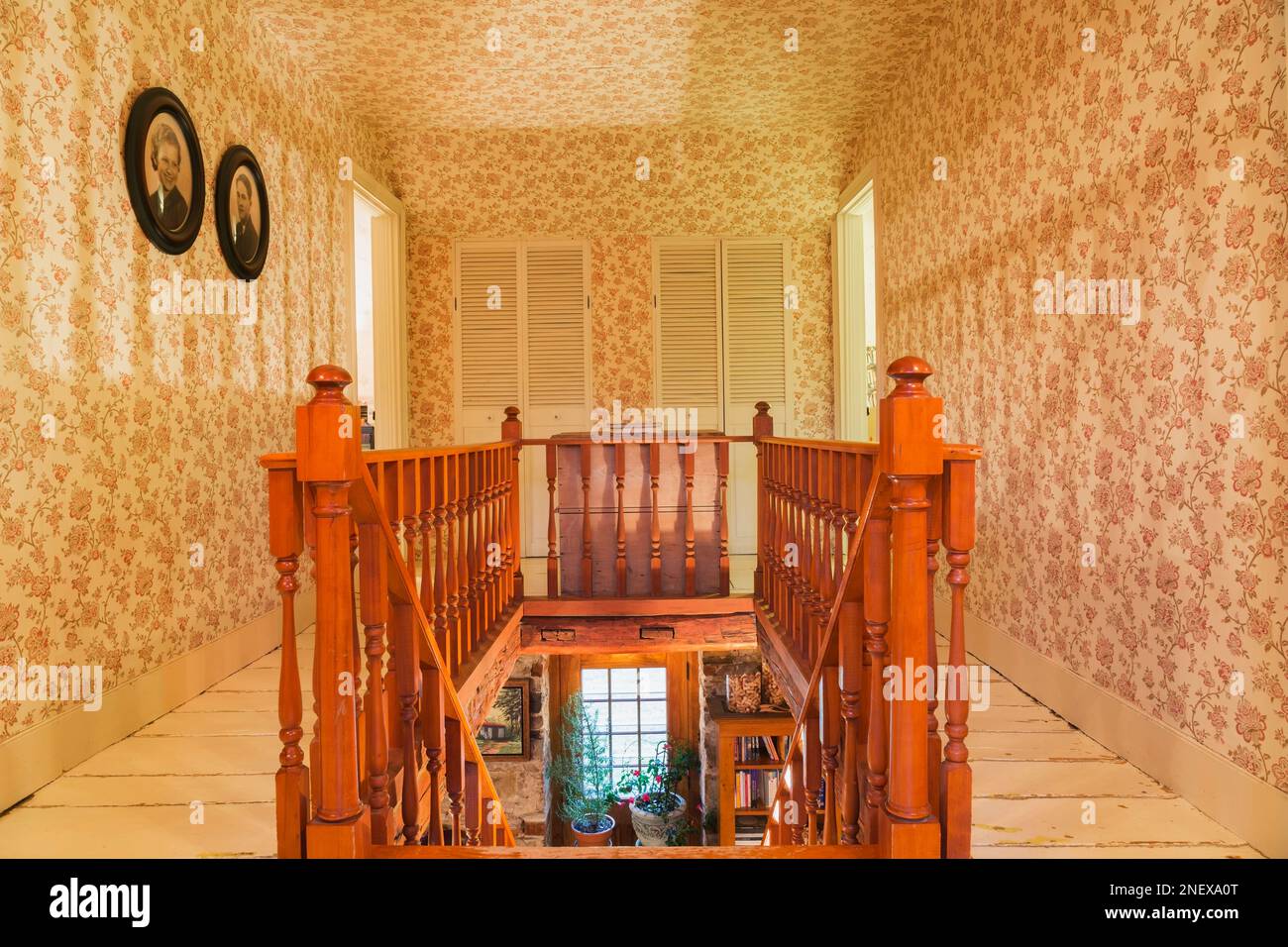 Stained pinewood staircase with railings on upstairs floor hallway with