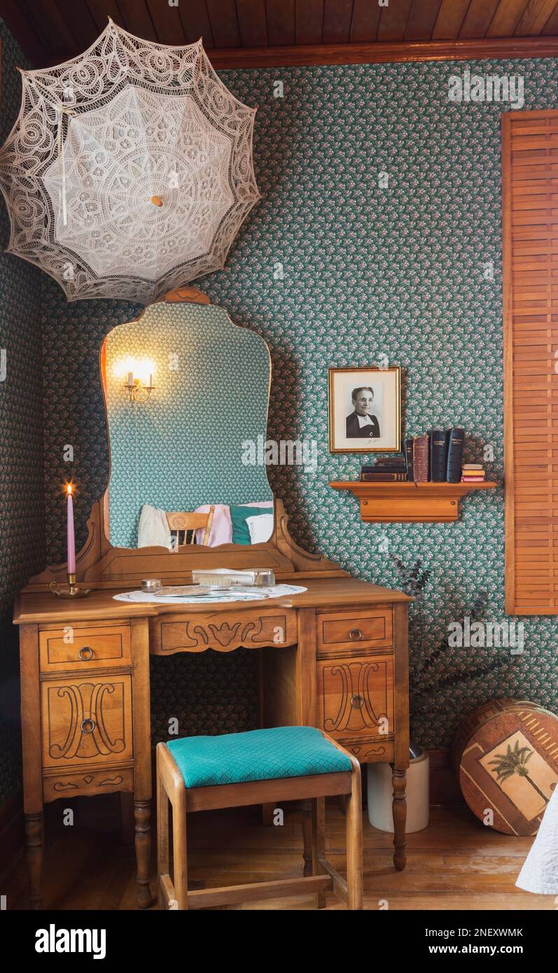 Antique wooden makeup table with sitting bench in guest bedroom on