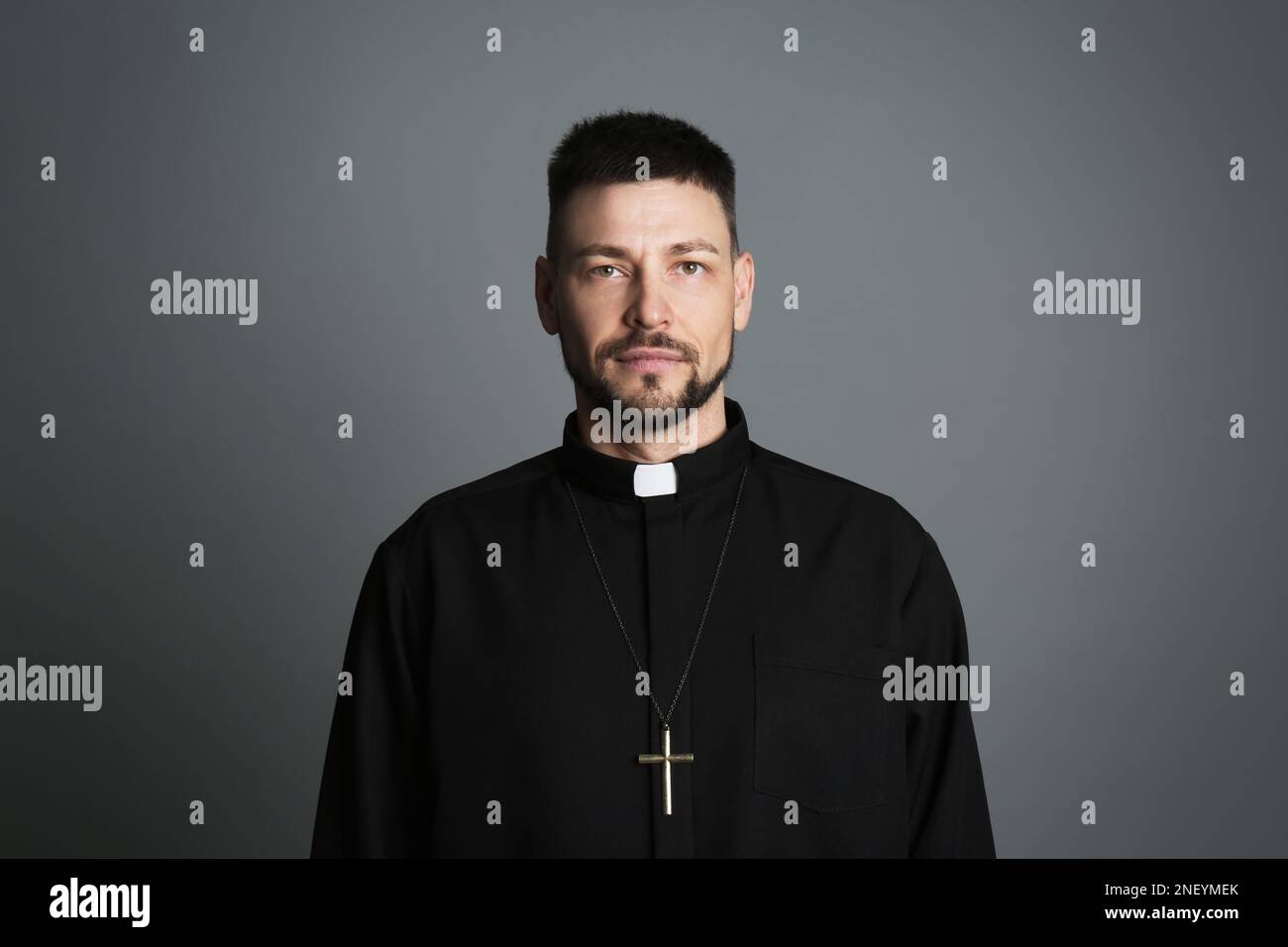 Priest wearing cassock with clerical collar on grey background Stock Photo