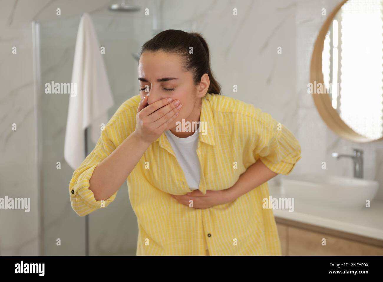 Young woman suffering from nausea in bathroom. Food poisoning Stock