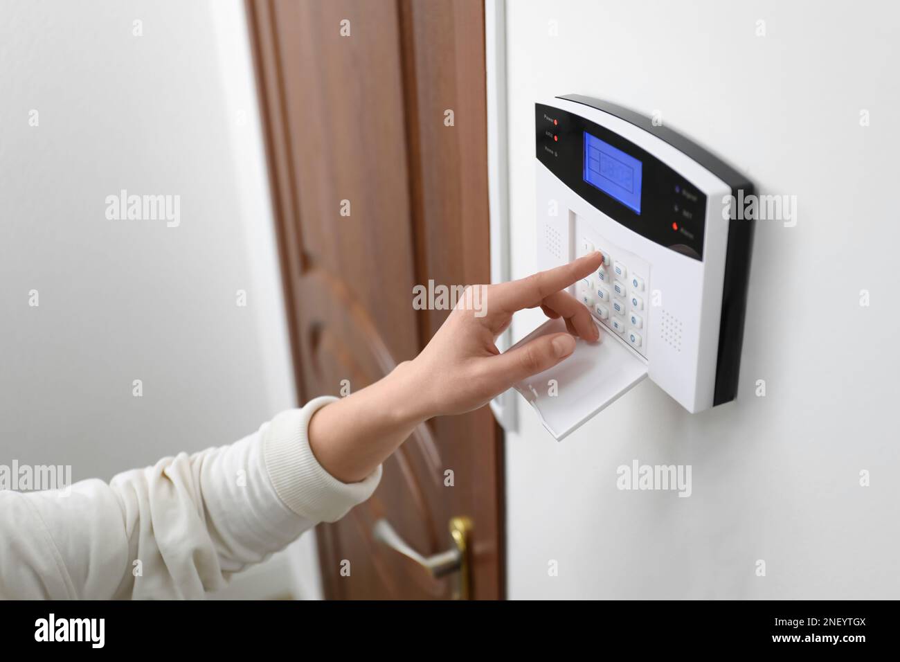 Woman entering code on home security system near door, closeup Stock Photo