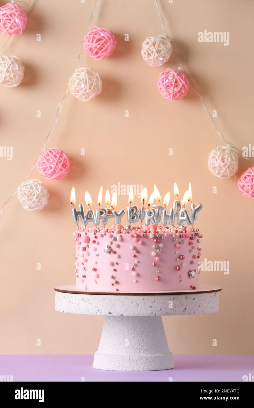 Birthday cake with burning candles on violet table Stock Photo - Alamy