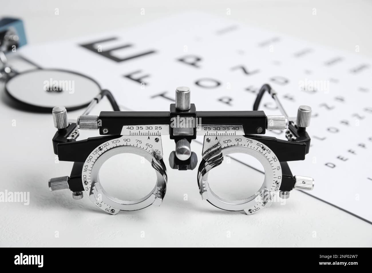 Trial frame, head mirror and eye chart test on white table