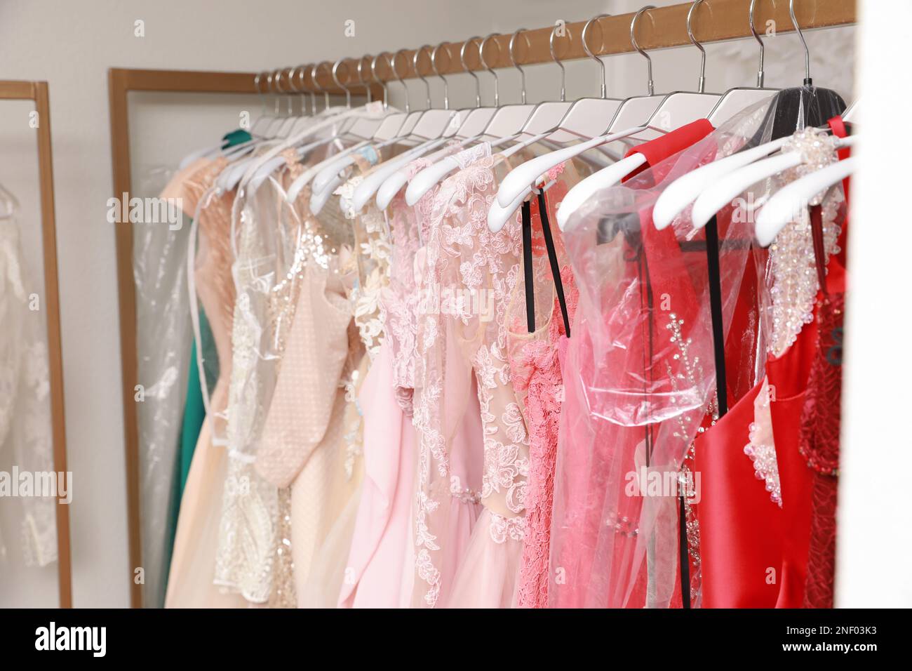 Different beautiful dresses on hangers in rental clothing salon Stock ...