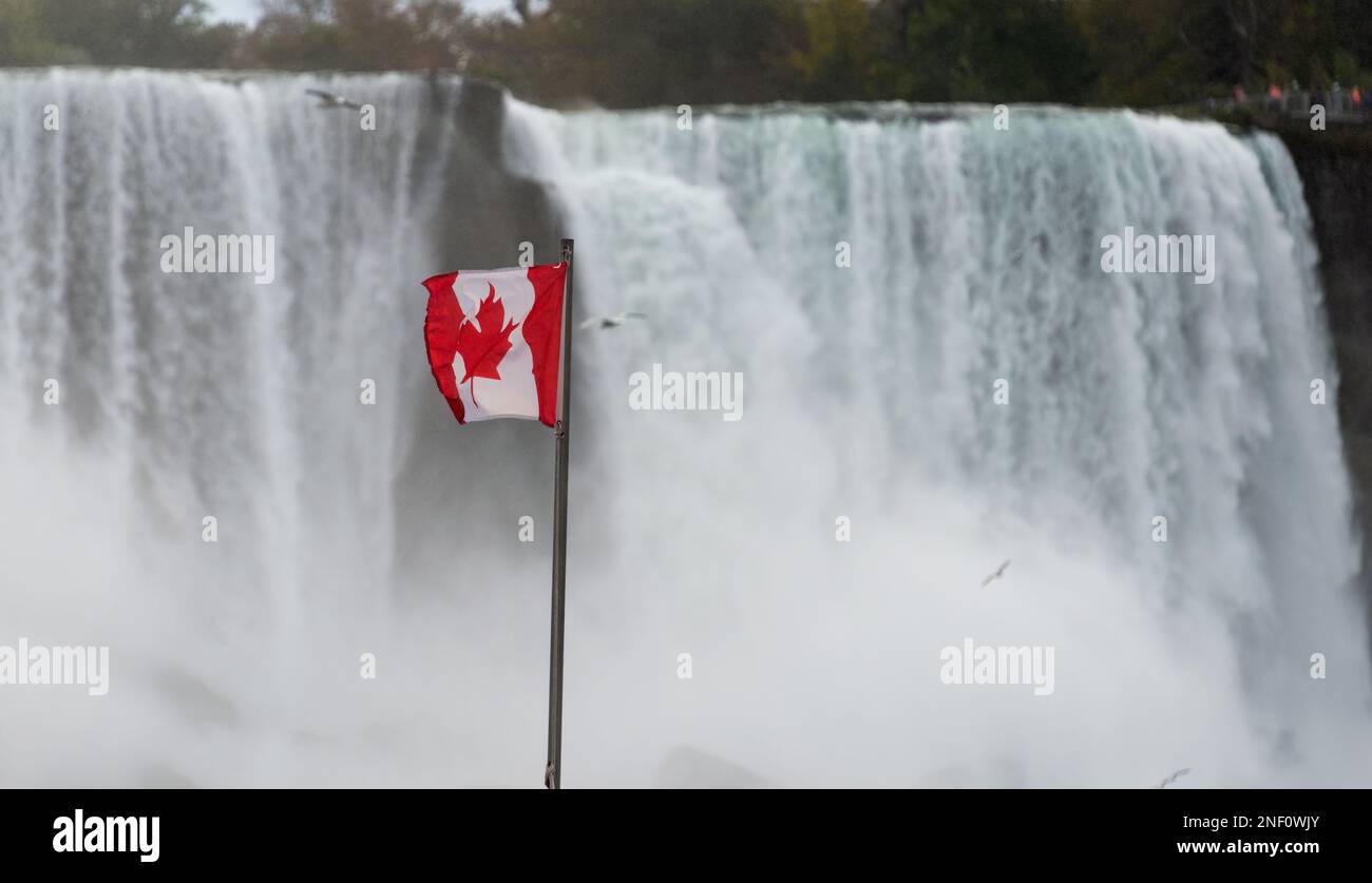 Canadian flag flying on flagpole at the side of Niagara Falls. Ontario, Canada. Stock Photo