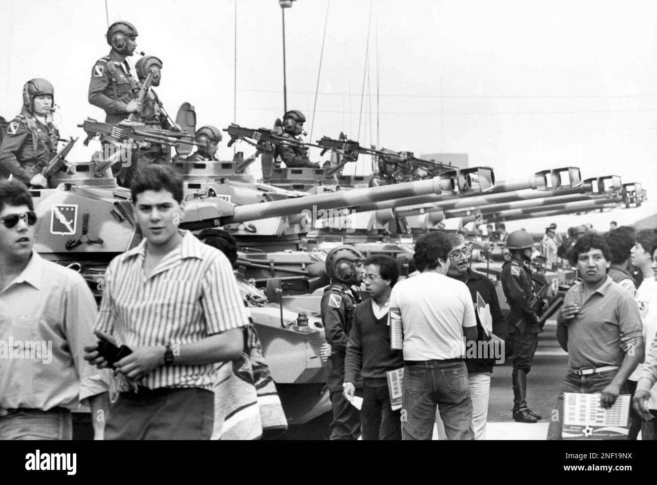 Mexican soldiers sit on tanks carefully watching the crowd as they