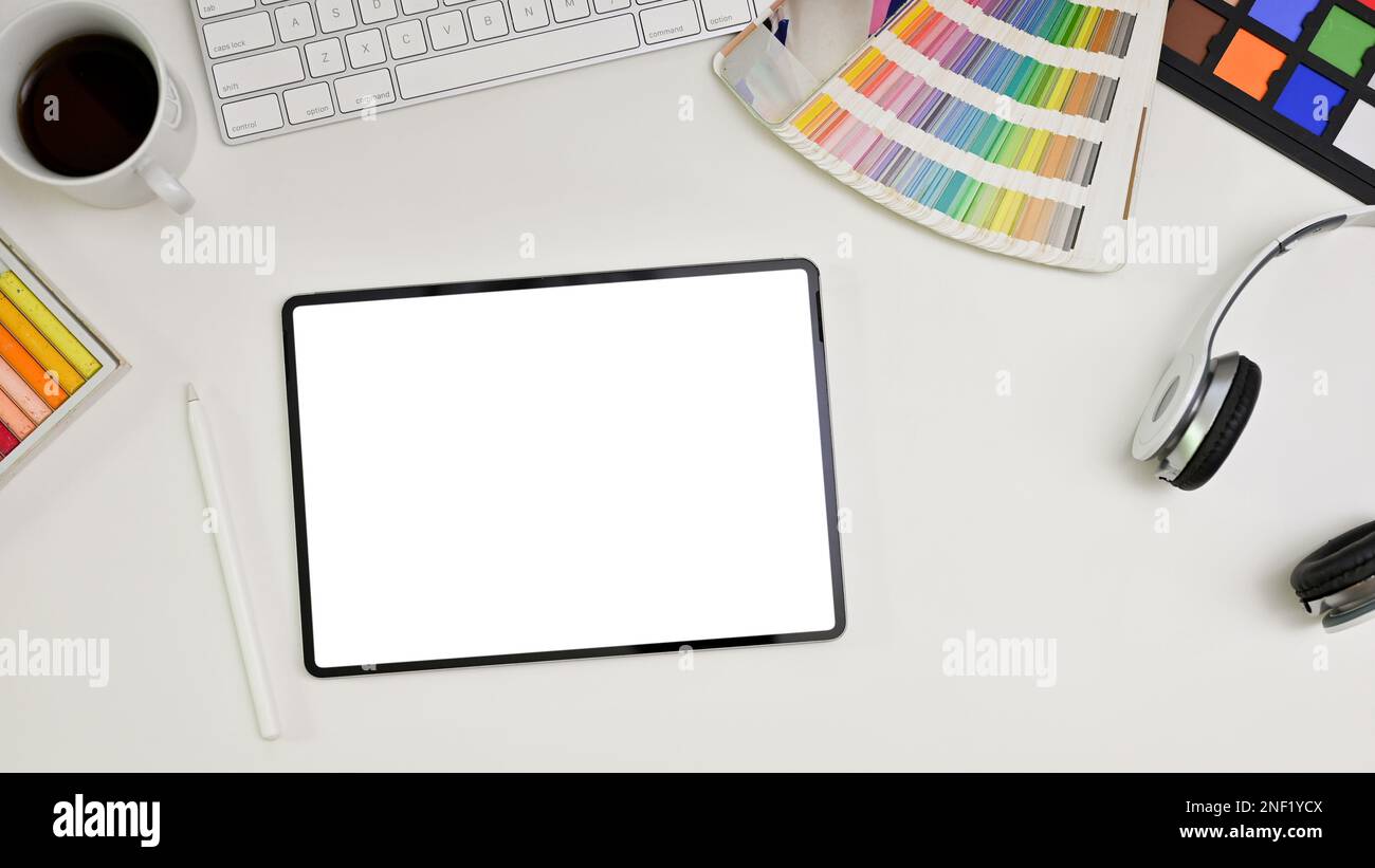 Top view of a modern minimal white graphic designer office desk with keyboard, headphones, color palette, color checker, stylus pen and digital tablet Stock Photo