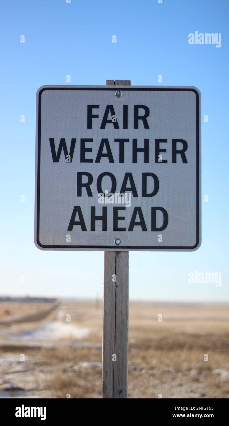 Driving Weather Signs A fair weather road ahead sign along a dirt road in Canada with ...