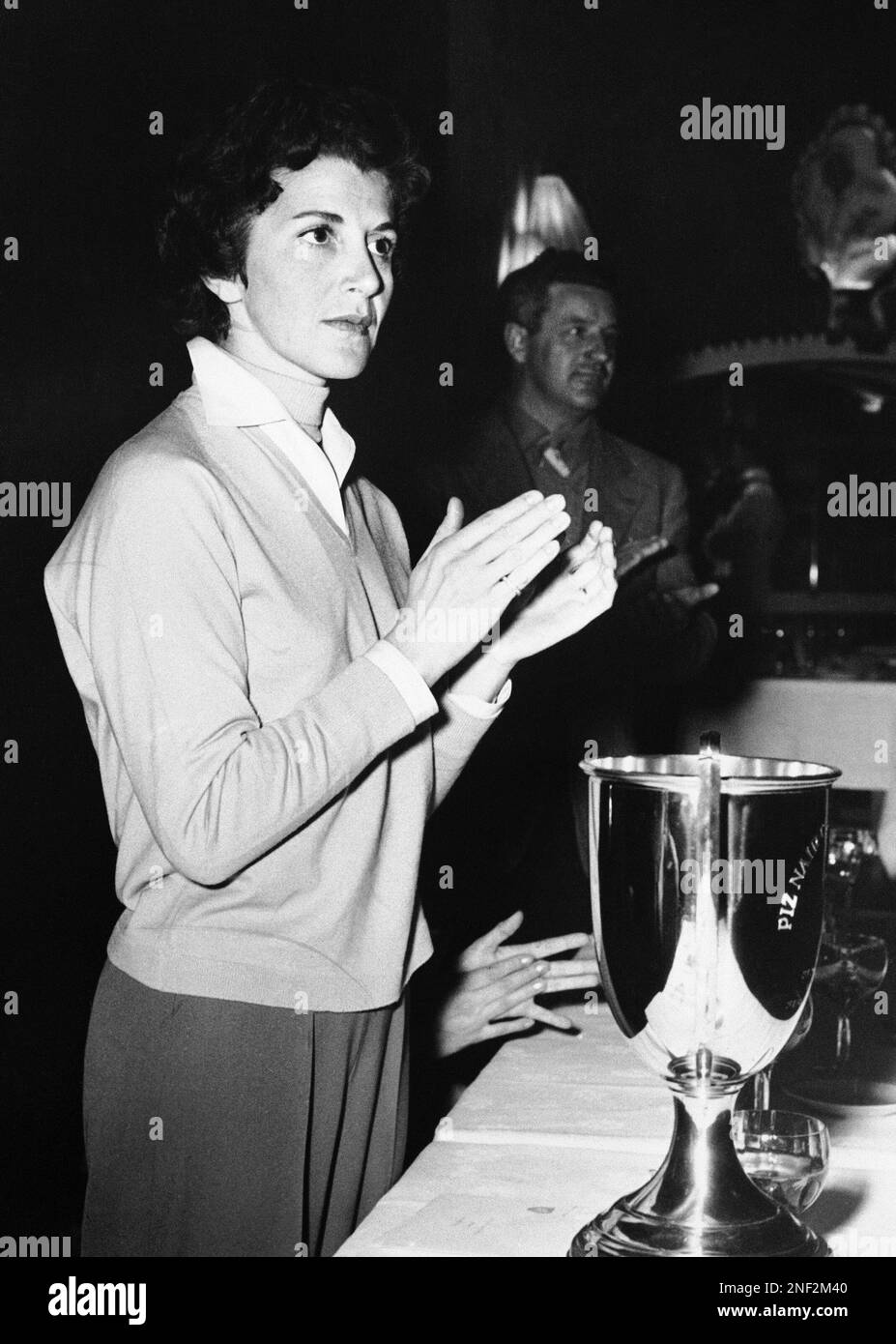 Madame Eugenia Niarchos, wife of the Greek shipping magnate Stavros  Niarchos stands behind the Piz Nair gold trophy at the Palace Hotel, St.  Mortiz, Switzerland on Feb. 24, 1957. She applauds winners