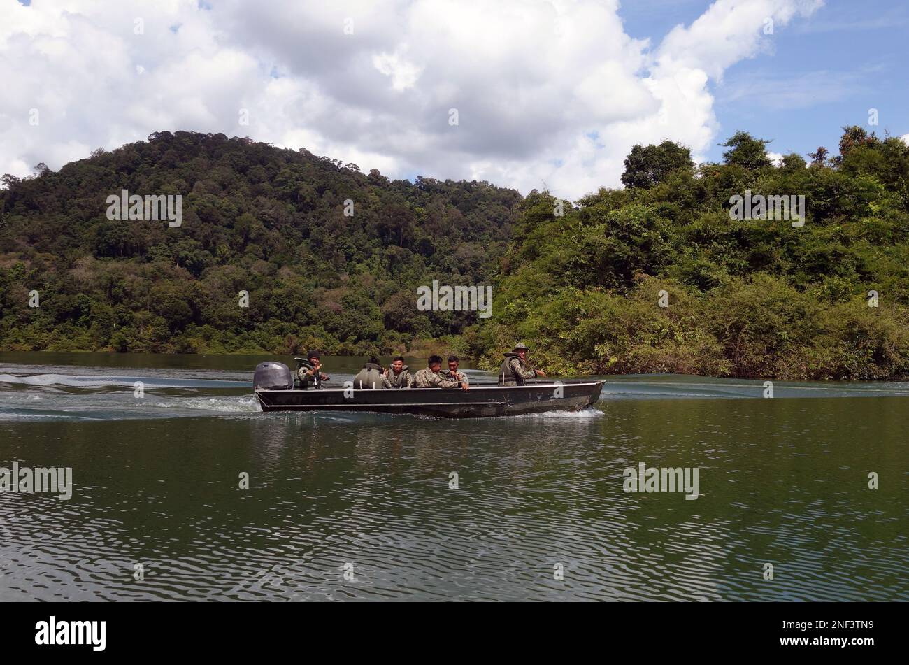 Army soldiers travelling by boat across Ulu Muda, near the Thai border, Peninsular Malaysia. No MR or PR Stock Photo