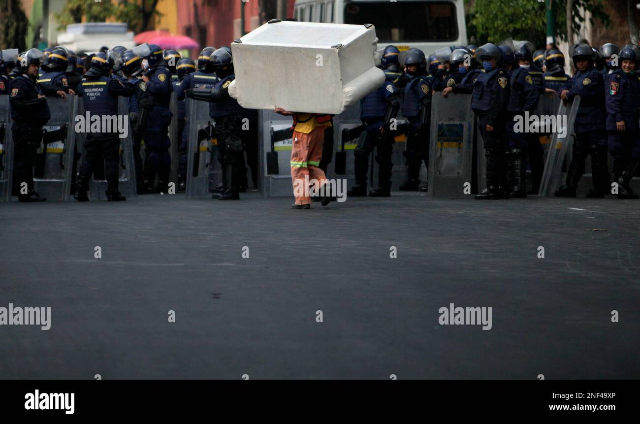 A man carries a sofa past rows of riot police during a mass eviction of ...