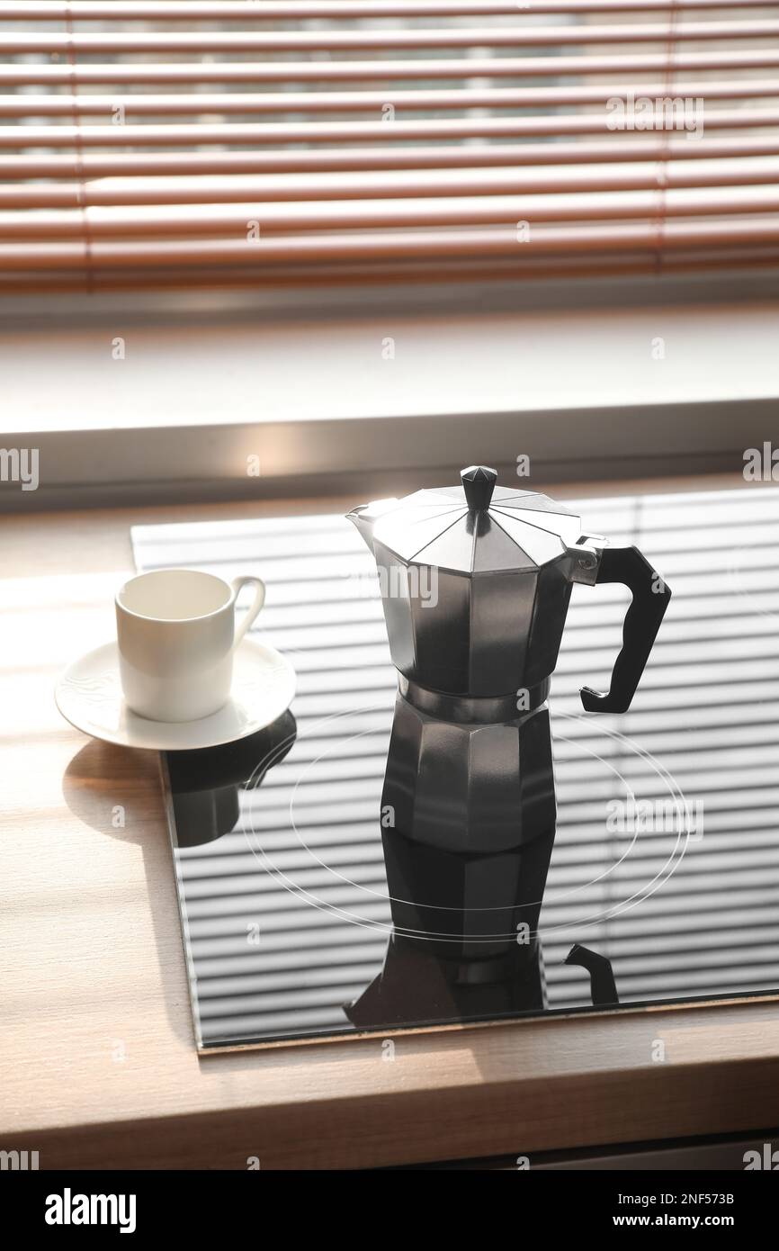 Geyser coffee maker on electric stove in kitchen near window Stock