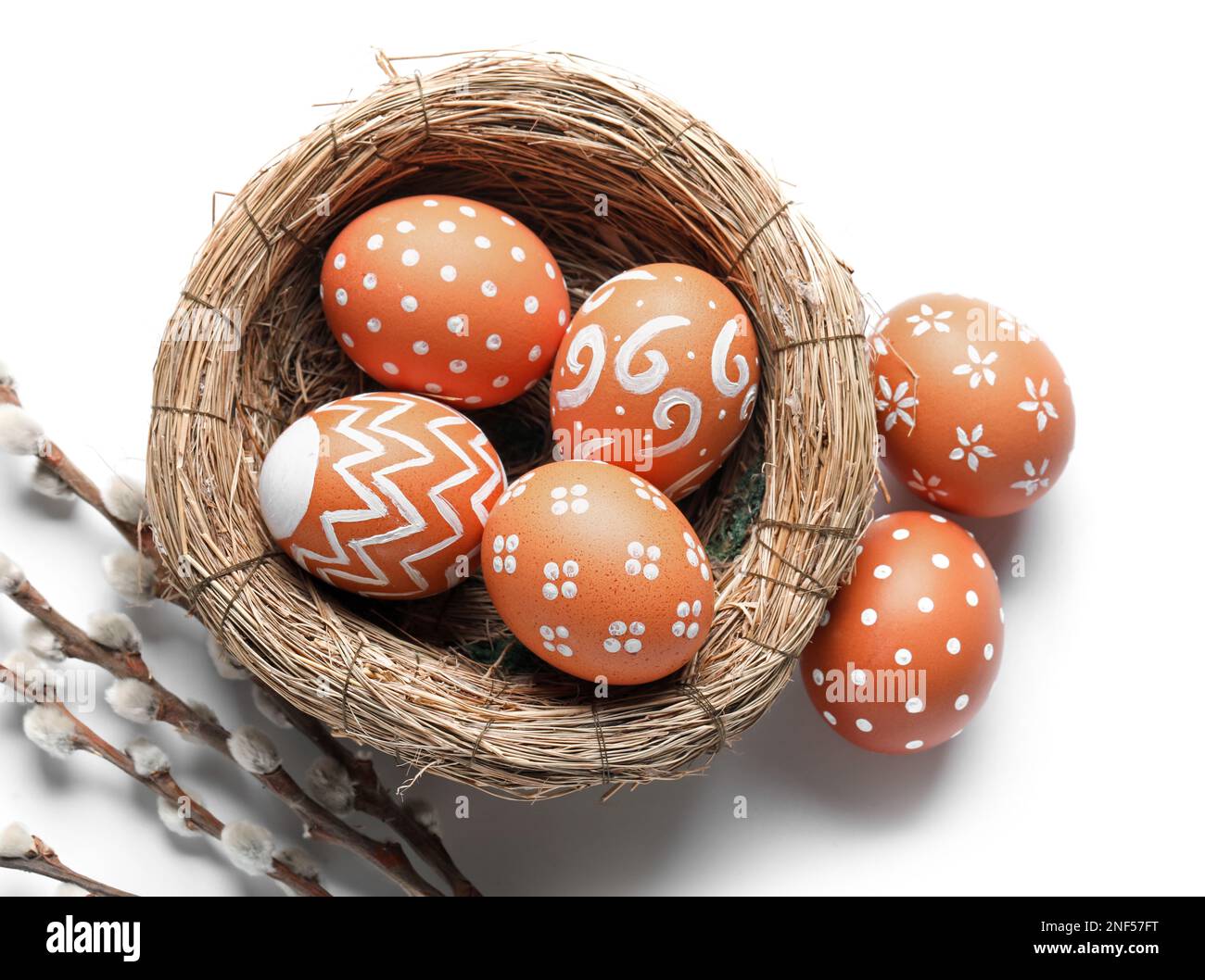 Nest of painted Easter eggs and willow branches on white background ...