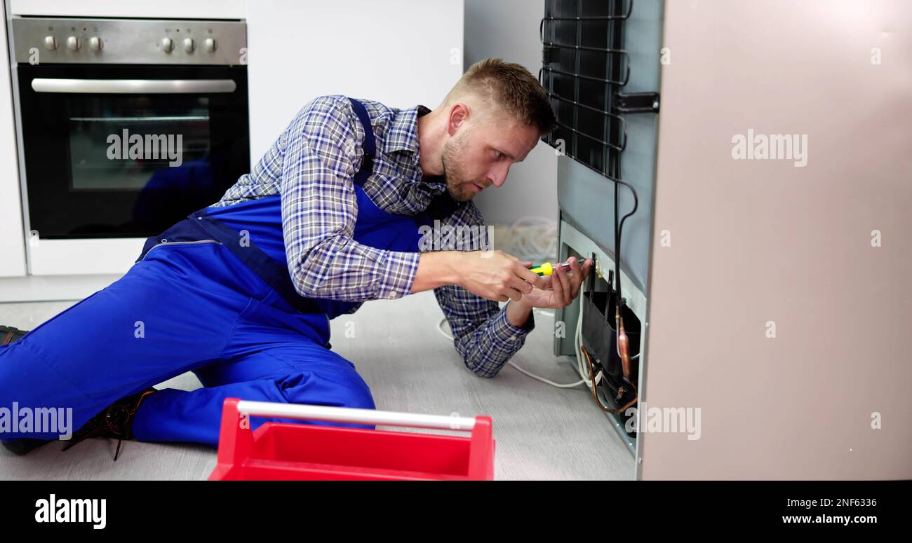 Cropped Image Of Serviceman Working On Fridge With Screwdriver At Home Stock Photo