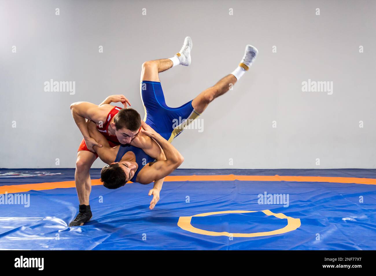 Two strong wrestlers in medical masks and wrestling tights are wrestlng on  a yellow wrestling carpet in the gym. Young man doing grapple.Sports con  Stock Photo - Alamy