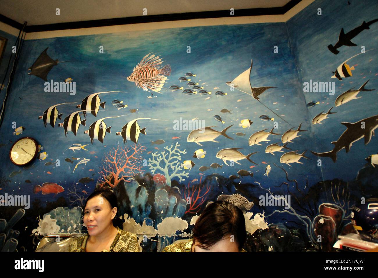 Receptionists respond to a query of a customer at the front desk of a seafood restaurant in Manado, a coastal city and the capital of North Sulawesi province of Indonesia. According to FAO in their latest report called The State of World Fisheries and Aquaculture 2022, Indonesia is the third largest producer of world's fisheries and aquaculture production of aquatic animals. Five countries—China, India, Indonesia, Vietnam, and Peru—are responsible for about 58 percent of the world's production. Indonesia is also one of the countries where aquatic foods contribute half or more of total... Stock Photo